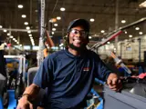 Team member smiling confidently at the camera sitting at a workbench