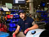 Team member at his workbench looking at the camera with confidence