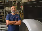 Team member confidently standing with arms crossed by a truck fender