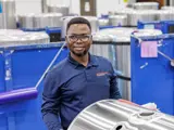 Team member looking at camera smiling while working on a truck gas tank