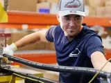 Team member working on the factory floor running hoses through a machine