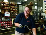 Team member smiling while working on a metal line part